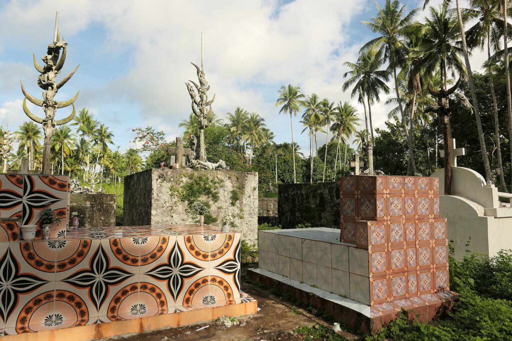 Gräber auf Osttimor mit Kreuz und Pfählen, die mit Büffelhörnern verzeirt sind