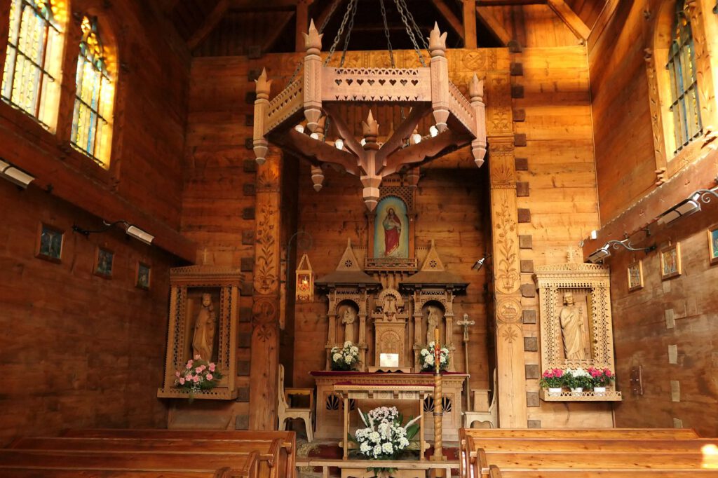 Verzierte Holzbalken, ein geschnitzter Holzaltar und einige Buntglasfenster in der Herz-Jesu-Kapelle