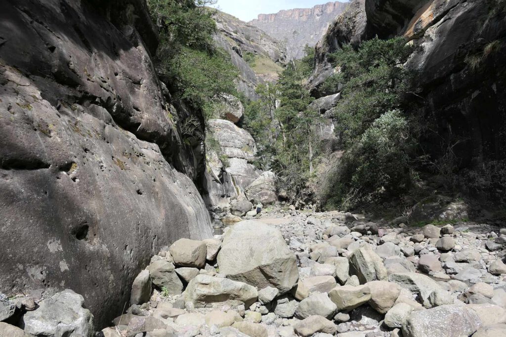 Springen über die im Flussbett liegenden Felsbrocken, um vorwärtszukommen in den Drakensbergen